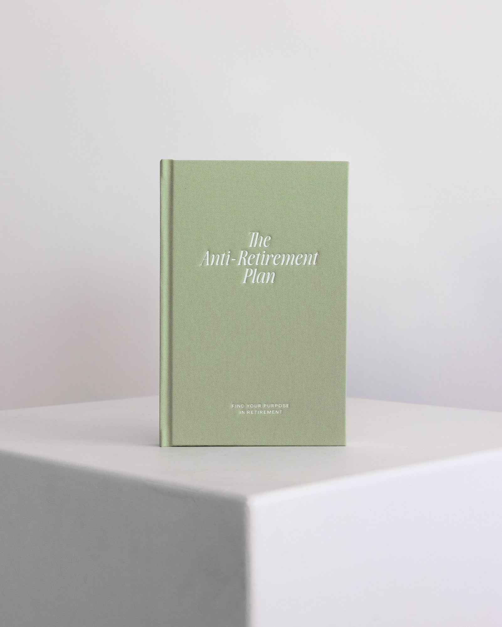 Green guided journal titled 'The Anti-Retirement Plan' on a white surface with a light gray background