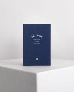 Blue book titled 'Bedside Business Plan' on a white surface with a light gray background