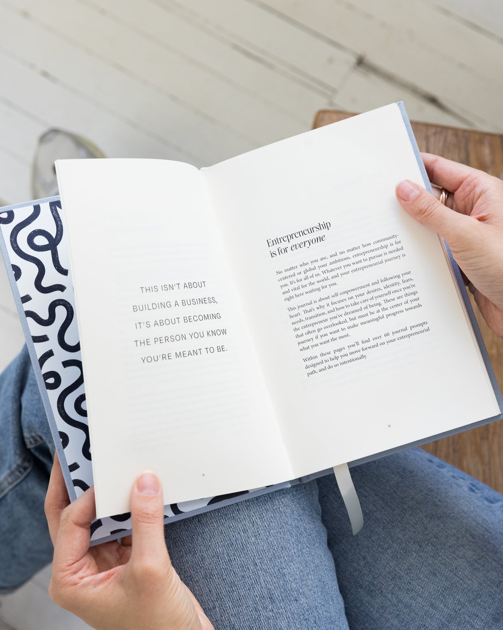 Person holding employee to entrepreneur guided journal open with text on a light background