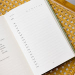 The Anti Retirement Plan Day Planner open on yellow chair