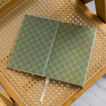 Green checkered The anti Retirement Plan notebook on a wicker chair