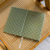 Green checkered The anti Retirement Plan notebook on a wicker chair