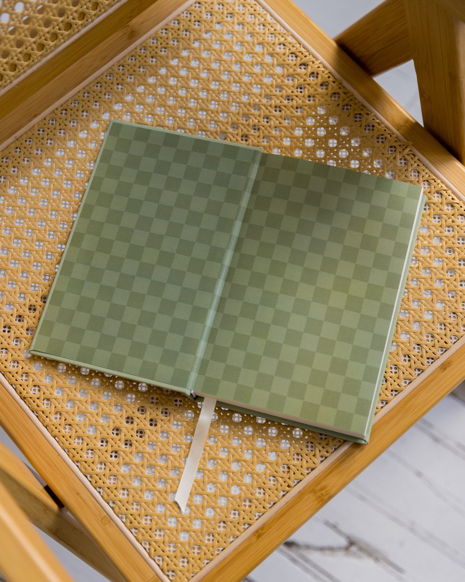 Green checkered The anti Retirement Plan notebook on a wicker chair